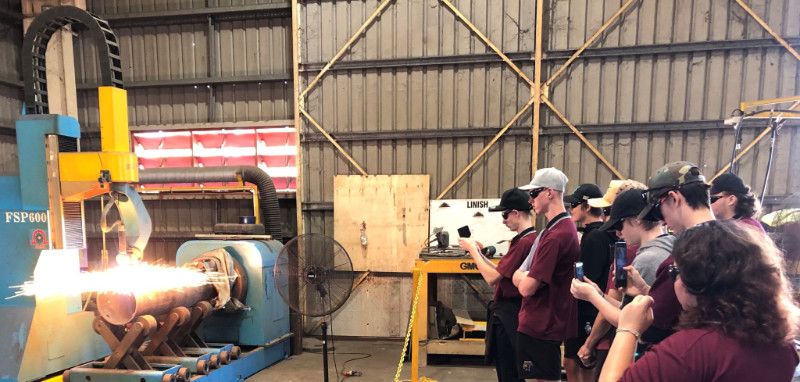 High school students recording and watching manufacturing machinery at global manufacturing group Gladstone.